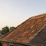 Close-up of terracotta clay roof tiles beside dark grey concrete tiles on a traditional Surrey home.